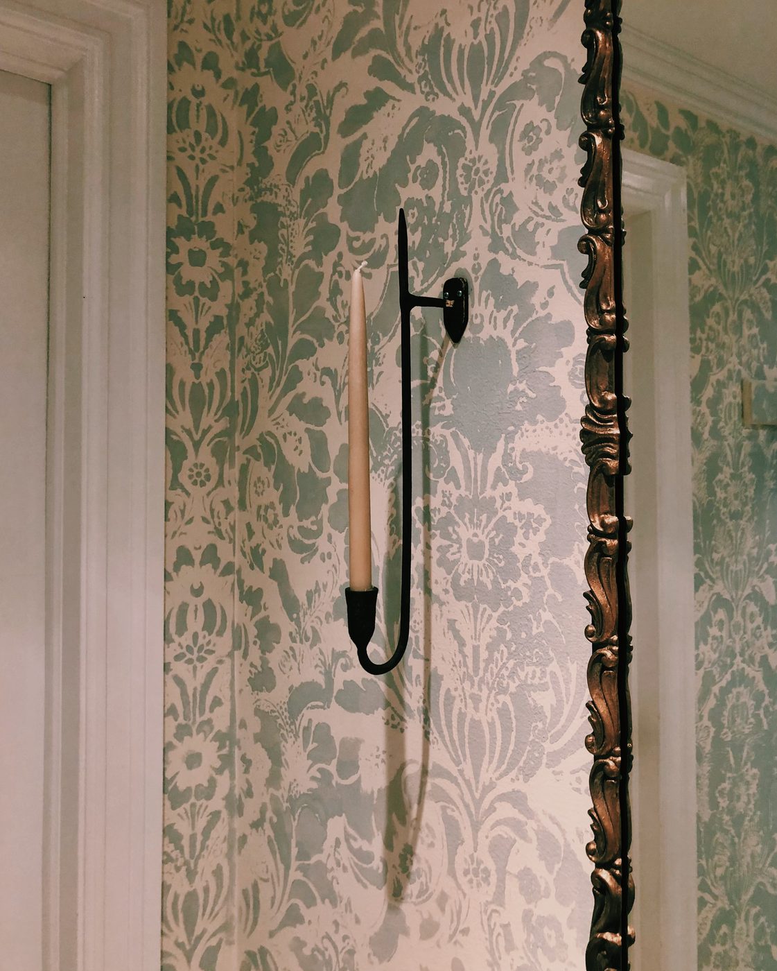 Candle sconce against damask stenciled wall