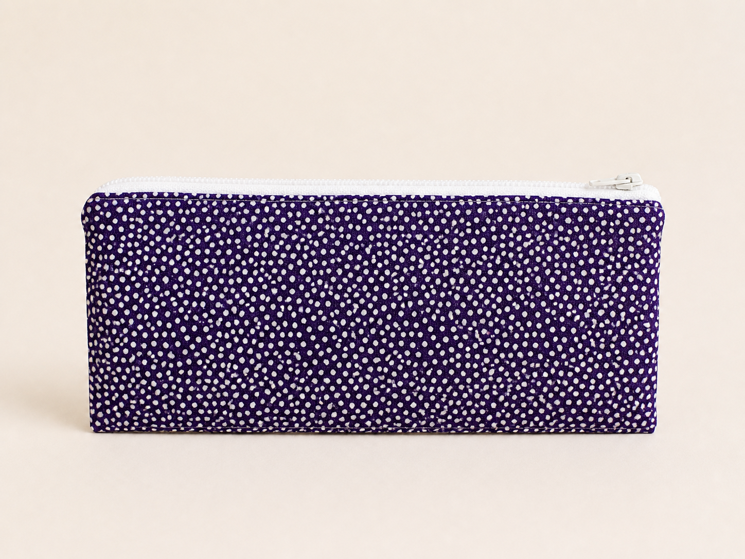 Deep purple polka dot pencil and cosmetics pouch on a clean studio background.