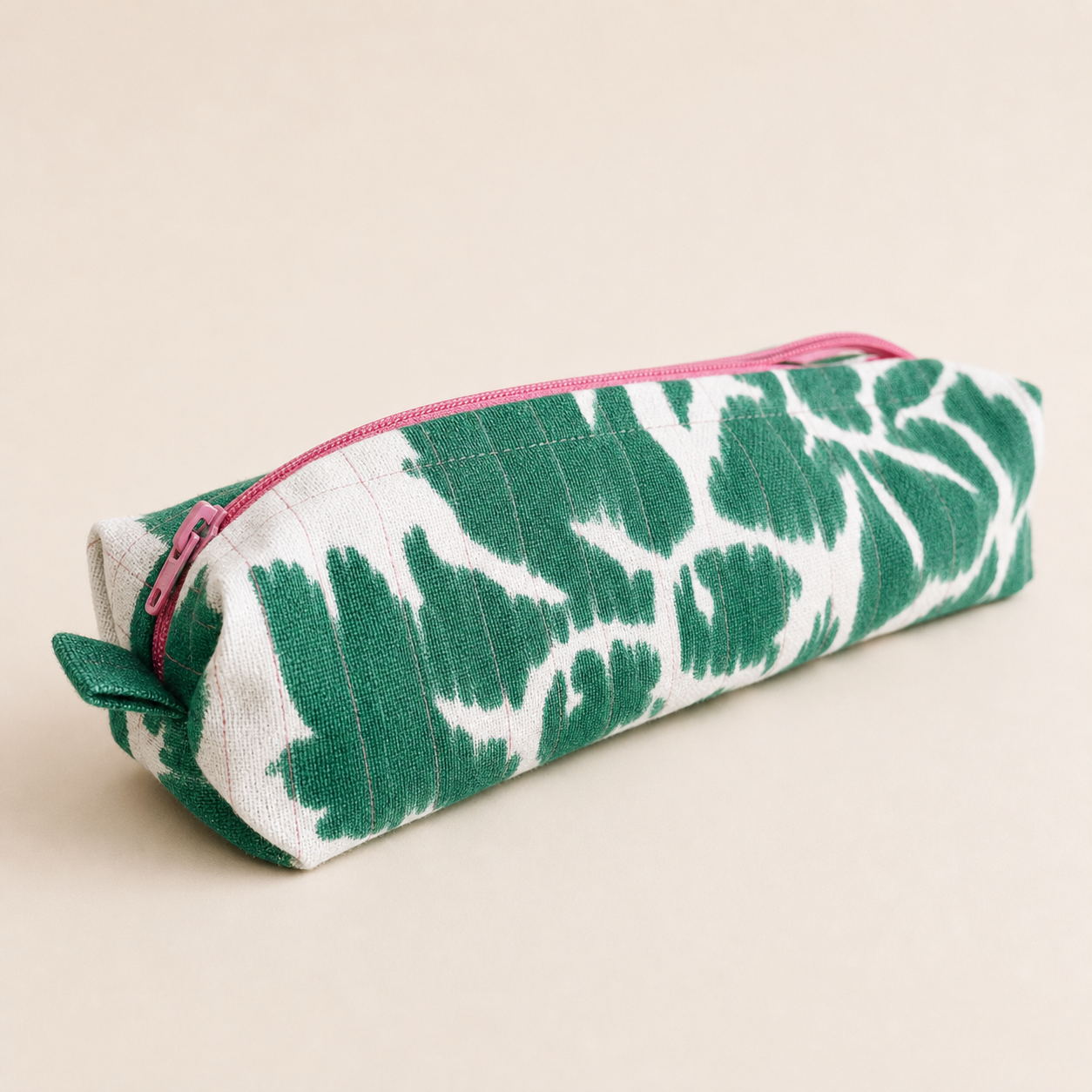 Green and white upcycled dinner napkin pencil case with a pink zipper on a clean studio background.